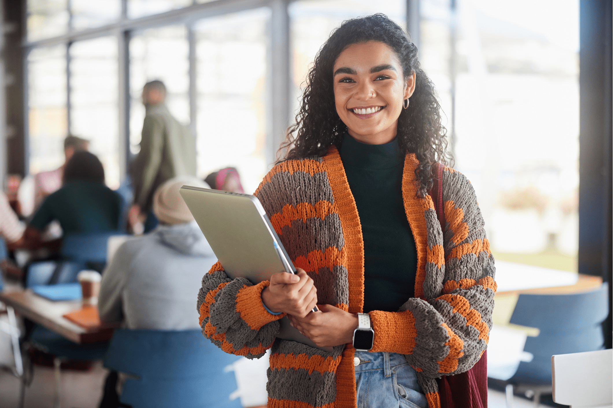Smiling woman holding a tablet in a casual setting.